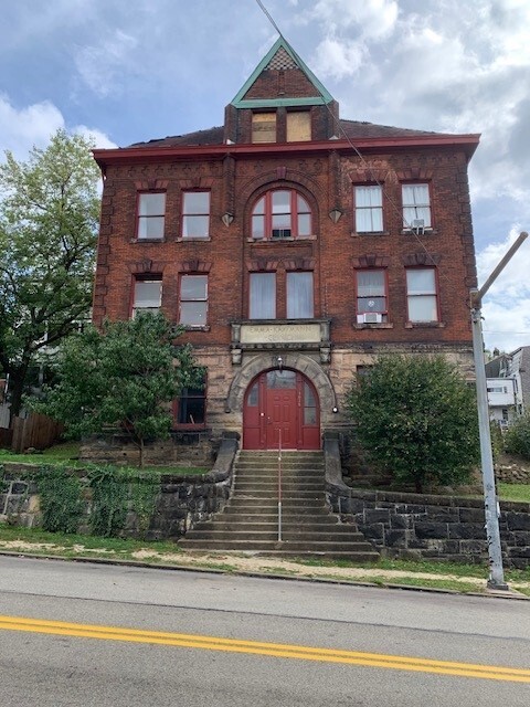 A photograph of a square three-story red brick building with a red door.