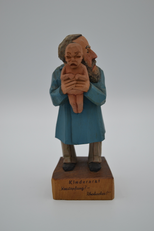 A wood figurine of pediatrician with inscription: "Constipation? - Rhubarb!" in German