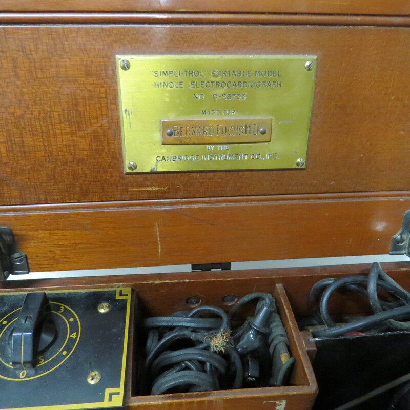 A wooden case with a handle and a brass plaque inscribed: "Made for Bernard Fuchs MD." Case contains portable electrocardiograph. Unlike earlier battery powered photographic models, this is an AC powered instrument.