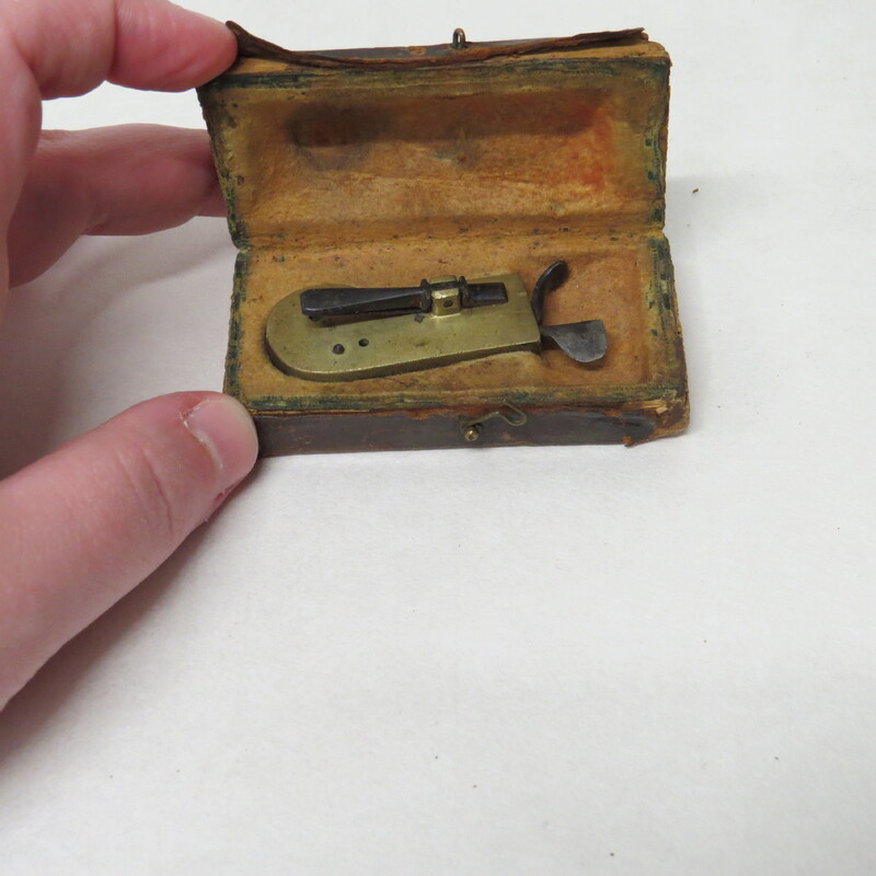 Brass spring lancet with steel lever release in typical case made of wood covered in leather and lined with chamois.