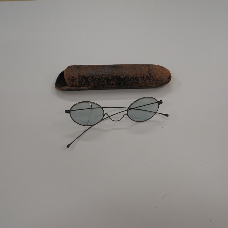 Tinted oval lenses in wire frames with 'W" bridge and straight temporal arms. One lens cracked. Partially readable label on case: Schaefer, & Optician, 250 Fifth Ave. Pittsburgh, PA