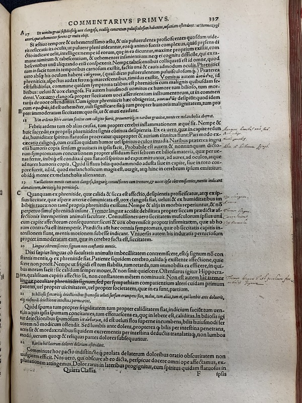 An old book, open to a page showing Latin text, underlines, and handwritten annotations.
