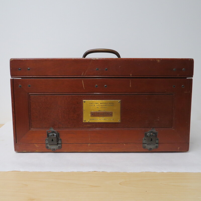 A wooden case with a handle and a brass plaque inscribed: "Made for Bernard Fuchs MD." Case contains portable electrocardiograph. Unlike earlier battery powered photographic models, this is an AC powered instrument.