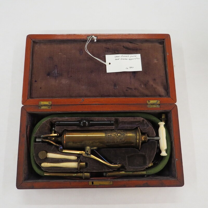 Surgical set. Set includes: 1 combined pump and enema syringe with bone handle and flute key lever, 1 enema tube, 2 oesophageal pipes, vulcanite mouth gag and wooden cap, 2 bone rectum pipes, cylinder attachment for stomach pump/enema apparatus, in wooden case with sage velvet lining and key.