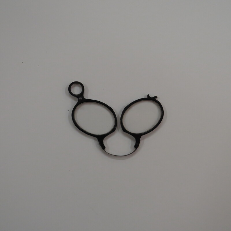 Typical eyeglasses, oval lenses in black frames with a spring clip and a pin to hold them when folded.