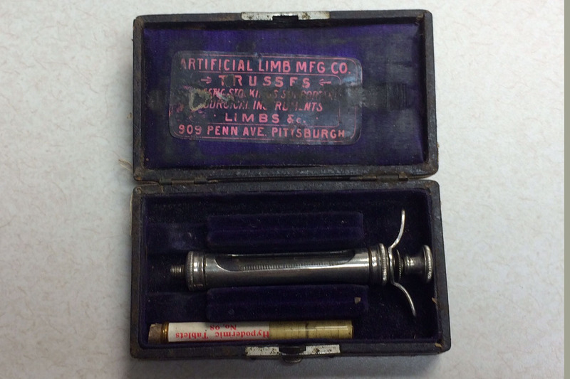 A syringe set in a leather covered case with a lock and Artificial Limb Manufacturing Company's label inside. 