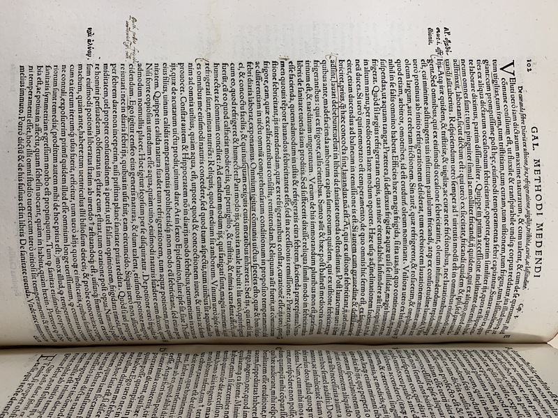 An old book, open to a page showing Latin text, underlines, and handwritten annotations.