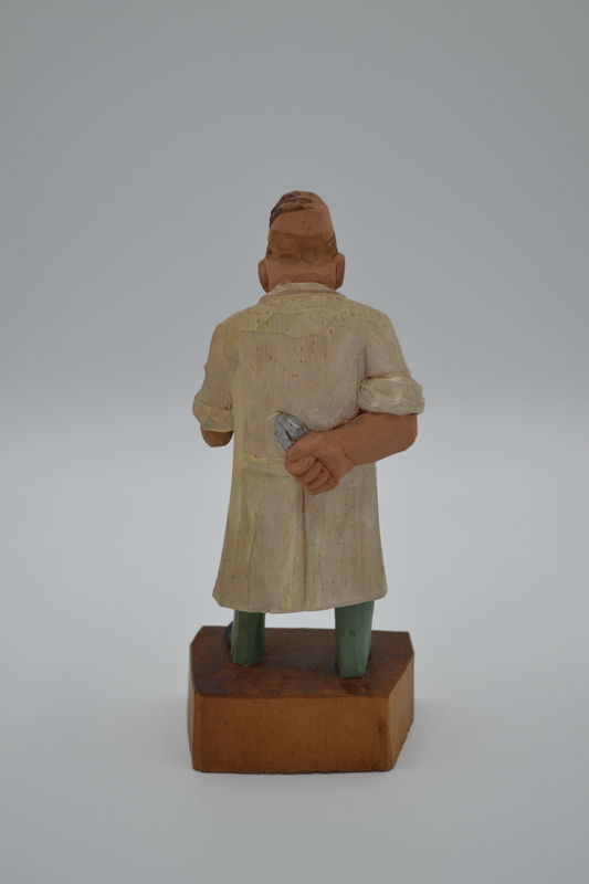 A wood figurine of dentist, holding tooth extracting forceps behind his back,  with inscription: "I'm not heartless, I pull painless" in German