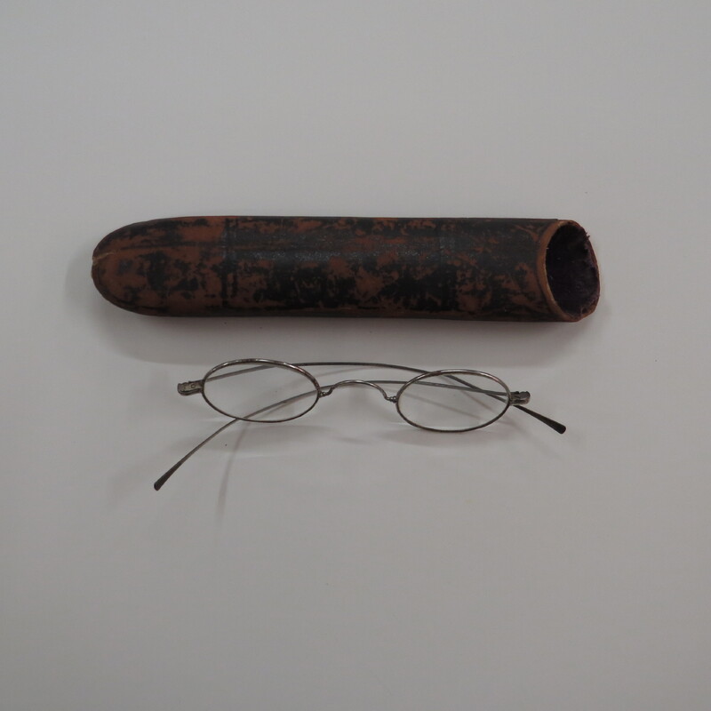 Oval lenses in metal frames with 'W" bridge and straight temporal arms with black and white eyeglasses case