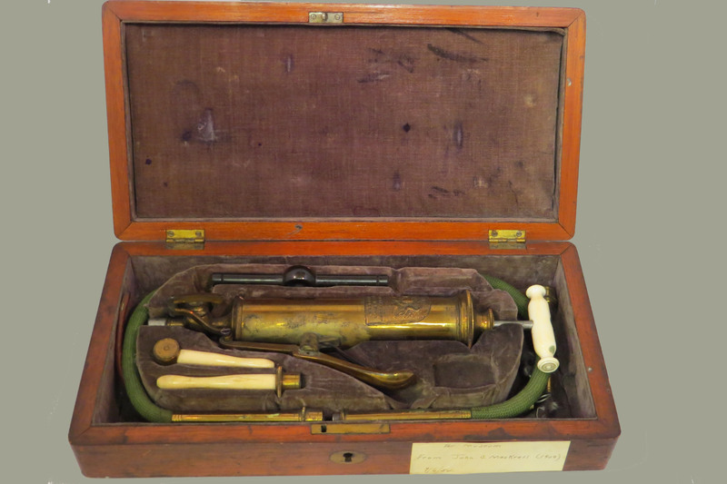 Surgical set. Set includes: 1 combined pump and enema syringe with bone handle and flute key lever, 1 enema tube, 2 oesophageal pipes, vulcanite mouth gag and wooden cap, 2 bone rectum pipes, cylinder attachment for stomach pump/enema apparatus, in wooden case with sage velvet lining and key.