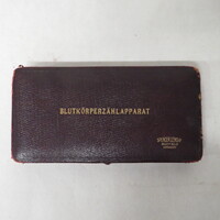  red box containing 4 glass pipettes with one relatively compelete hose connecter shape like item, lens reads improved Neubeuer .