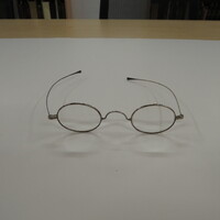 Oval lenses in metal frames with 'W" bridge and straight temporal arms.