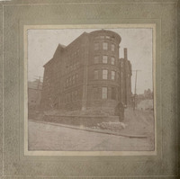 Black-and-white photo of a four-story brick building with a round addition on its front.